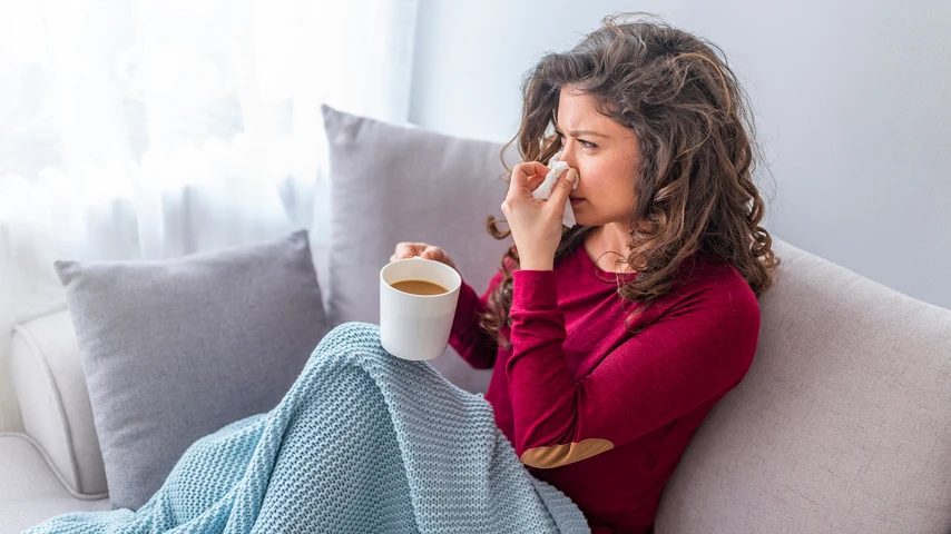 Asian woman has runny and common cold. Cough. Closeup Of Beautiful Young Woman Caught Cold Or Flu Illness. Portrait Of Unhealthy Girl In Scarf Feeling Pain In Throat.